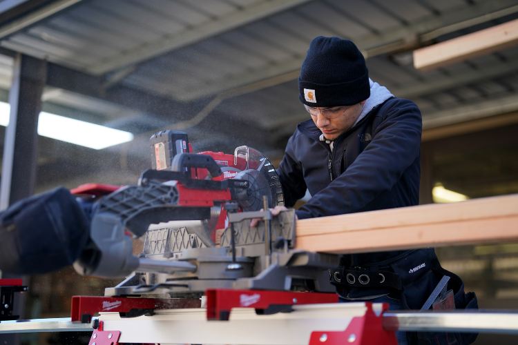 Anthony Sousa using a saw to cut a piece of wood