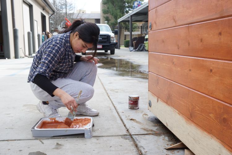 Jaqueline Molina Berber painting a side of the booth 