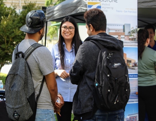 Company representative speaking with two students at the annual welcome back bbq and industry expo 