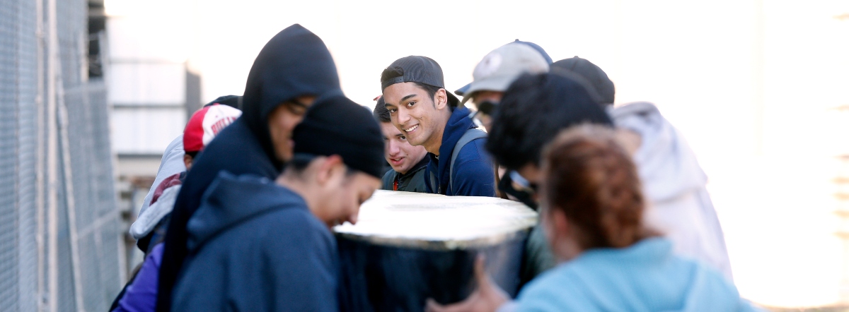 Group of students work on project with one smiling at camera