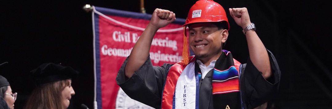 graduate raises arms in celebration