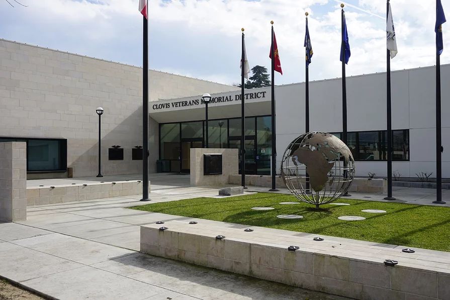 Clovis Veterans Memorial District Exterior of the Clovis Veterans Memorial District building with flags and globe sculpture.