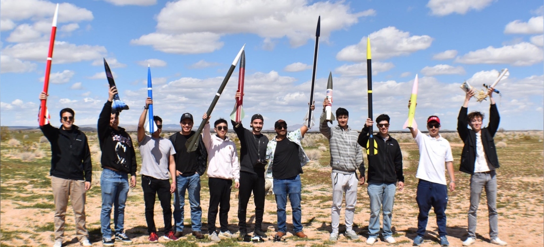 Engineering students holding up rockets 